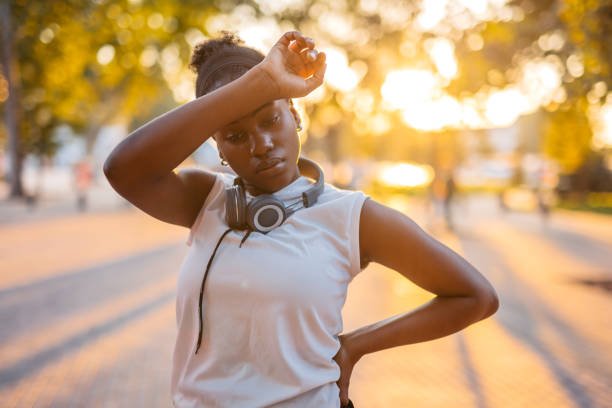 Beautiful young black woman exhausted after jogging in the park.